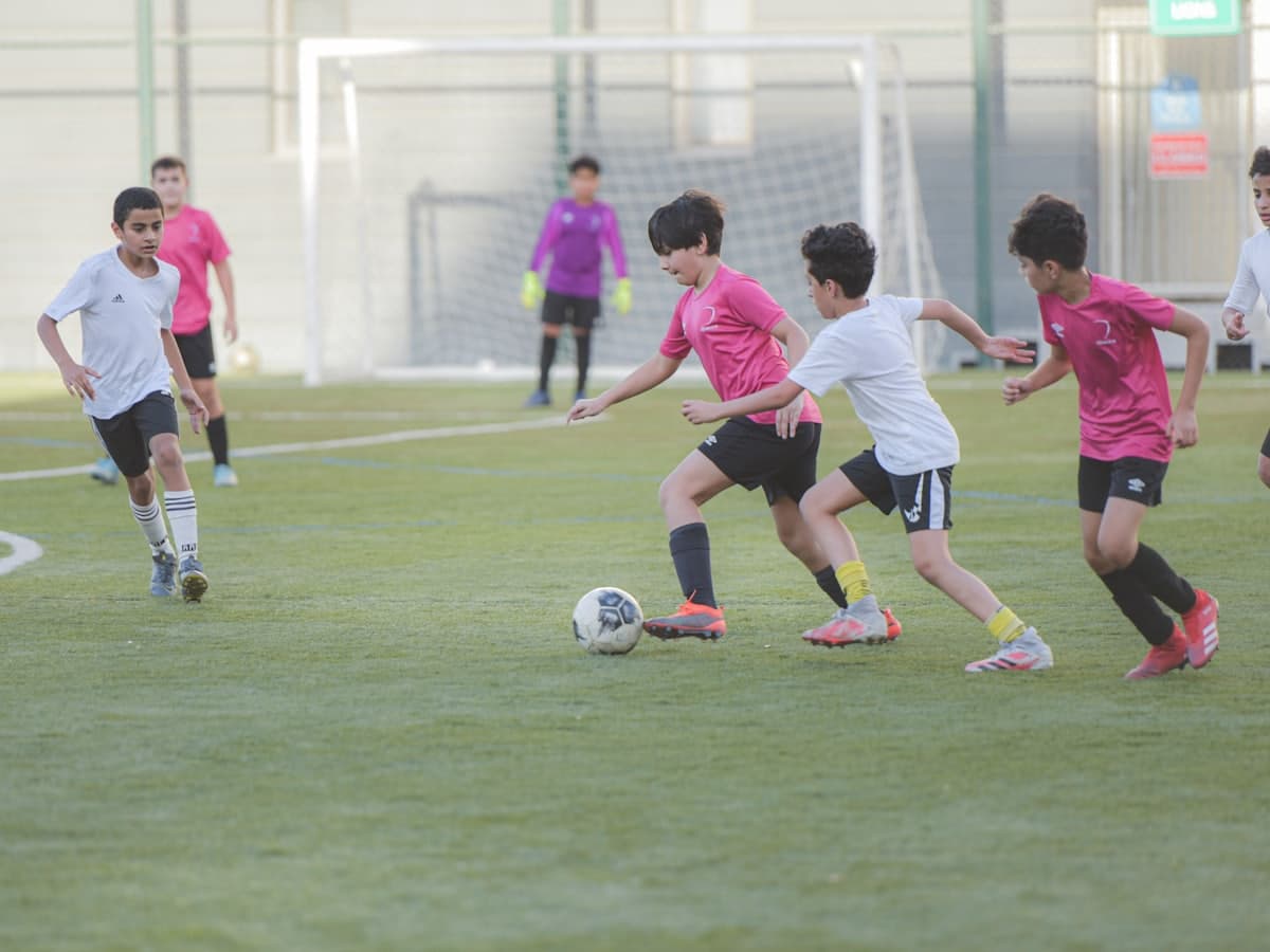 Children playing a football match on a pitch at an academy