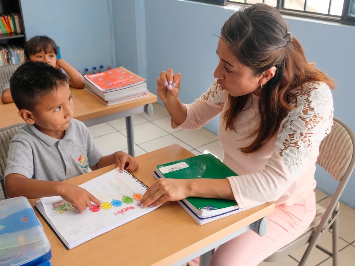 A teacher working one-to-one with a young student at a desk