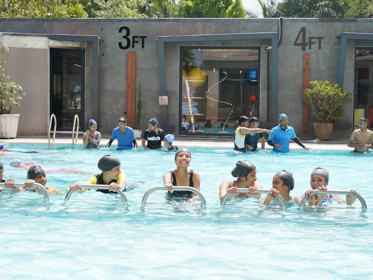 Children at a group swimming lesson holding the poolside rail